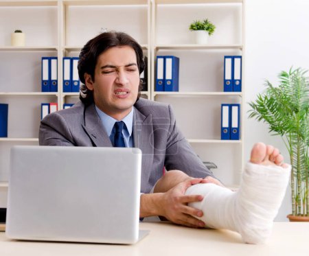 Téléchargez les photos : L'employé blessé à la jambe travaillant au bureau - en image libre de droit