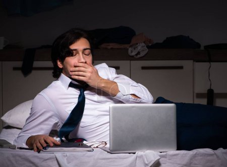 Téléchargez les photos : Le jeune salarié travaillant à domicile après son poste de nuit - en image libre de droit