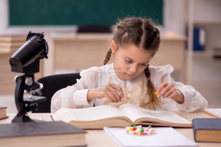 Téléchargez les photos : Little girl in drugs synthesis concept in the classroom - en image libre de droit