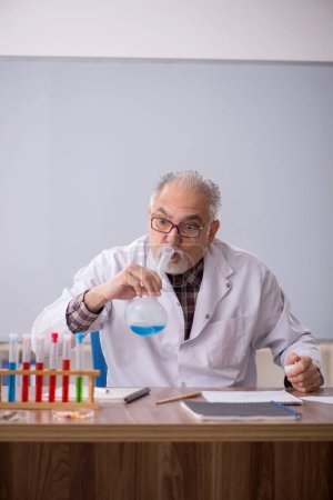 Photo for Old teacher chemist sitting in the classroom - Royalty Free Image