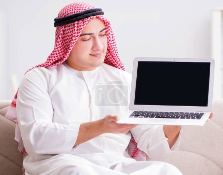 Foto de El joven hombre de negocios árabe que trabaja con el ordenador portátil en el sofá - Imagen libre de derechos