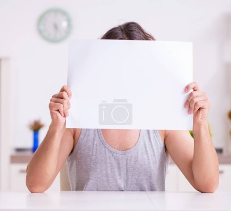 Foto de Joven sosteniendo papel en blanco en la casa - Imagen libre de derechos