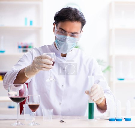 Foto de El químico masculino examinando muestras de vino en el laboratorio - Imagen libre de derechos