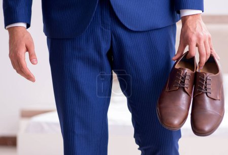Foto de El joven hombre de negocios guapo eligiendo zapatos en casa - Imagen libre de derechos
