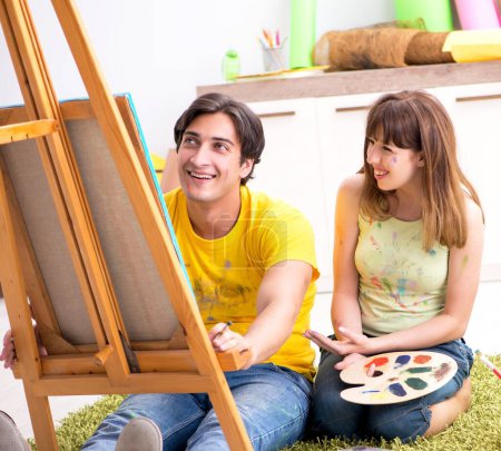 Foto de La joven pareja disfrutando de la pintura en casa - Imagen libre de derechos