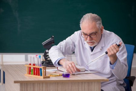 Photo for Old chemist teacher sitting in the classroom - Royalty Free Image