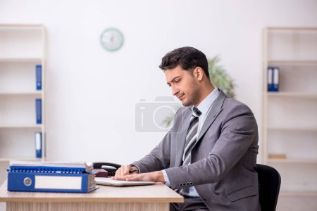 Téléchargez les photos : Jeune employé assis sur le lieu de travail - en image libre de droit