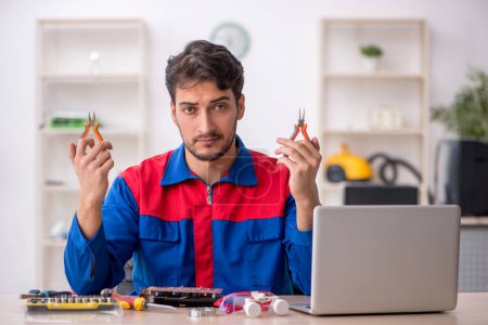 Téléchargez les photos : Jeune réparateur réparer l'ordinateur au laboratoire - en image libre de droit