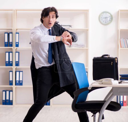 Foto de El joven empleado masculino en la oficina en concepto de gestión del tiempo - Imagen libre de derechos