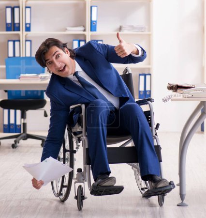 Foto de El joven empleado en silla de ruedas que trabaja en la oficina - Imagen libre de derechos