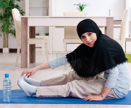 Téléchargez les photos : La jeune femme en hijab faisant des exercices à la maison - en image libre de droit