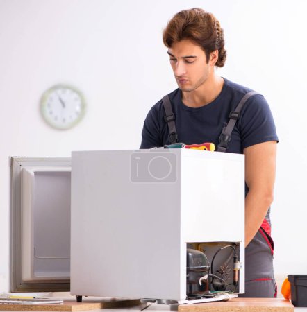 Téléchargez les photos : Le jeune entrepreneur beau réparer réfrigérateur - en image libre de droit