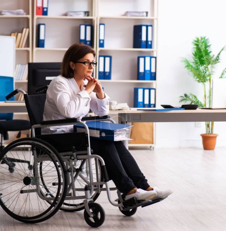 Téléchargez les photos : L'employée en fauteuil roulant au bureau - en image libre de droit