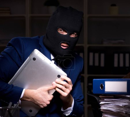 Téléchargez les photos : L'employé masculin vole des informations dans le bureau la nuit - en image libre de droit
