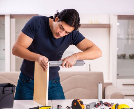Photo for The young man repairing furniture at home - Royalty Free Image