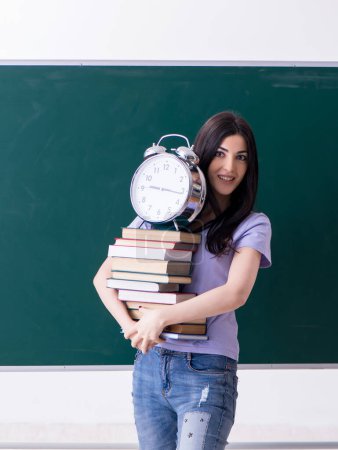 Téléchargez les photos : La jeune étudiante enseignante devant le green board - en image libre de droit