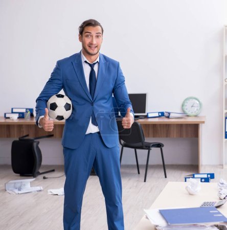 Photo for Young employee playing football in the office - Royalty Free Image