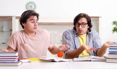 Téléchargez les photos : Les deux étudiants masculins se préparent aux examens à la maison - en image libre de droit