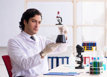 Foto de El joven químico guapo que trabaja en el laboratorio - Imagen libre de derechos