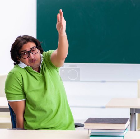 Photo for The male student suffering from urge in the classroom - Royalty Free Image