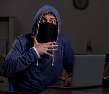 Photo for Male hacker hacking security firewall late in the office - Royalty Free Image