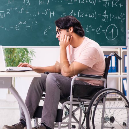 Foto de The young handsome man in wheelchair in front of chalkboard - Imagen libre de derechos