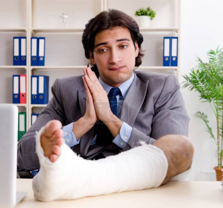 Photo for The leg injured employee working in the office - Royalty Free Image