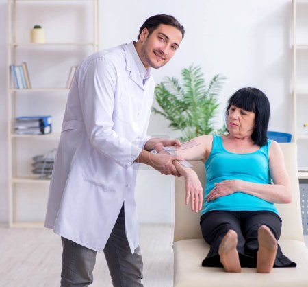 Photo for The young male doctor examining old female patient - Royalty Free Image