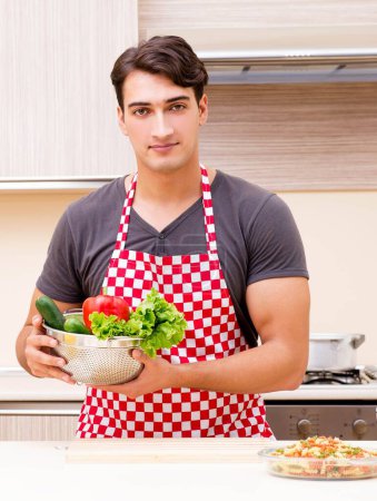 Foto de El hombre cocinero masculino preparando la comida en la cocina - Imagen libre de derechos