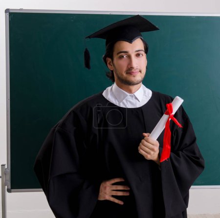 Photo pour L'étudiant diplômé devant le tableau vert - image libre de droit