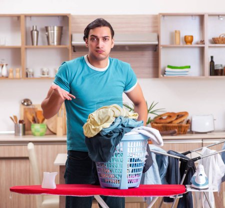 Photo for The young man husband doing clothing ironing at home - Royalty Free Image