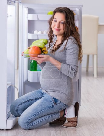 Photo for The pregnant woman near fridge looking for food and snacks - Royalty Free Image