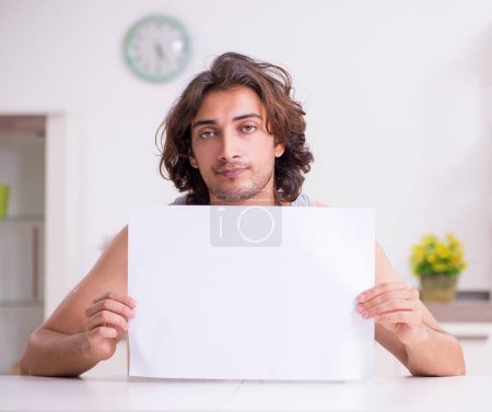Photo for Young man holding blank paper at the home - Royalty Free Image