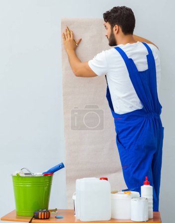 Foto de El trabajador que trabaja en el papel pintado durante la renovación - Imagen libre de derechos