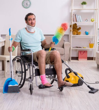 Photo for The young man in wheel-chair cleaning the house - Royalty Free Image