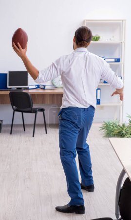 Photo for Young employee throwing rugby ball in the office - Royalty Free Image