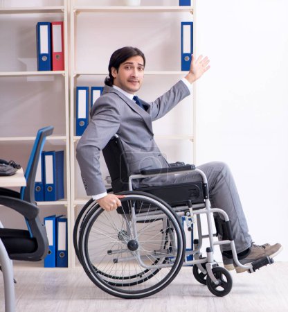 Téléchargez les photos : Le jeune et beau employé en fauteuil roulant travaillant dans le bureau - en image libre de droit