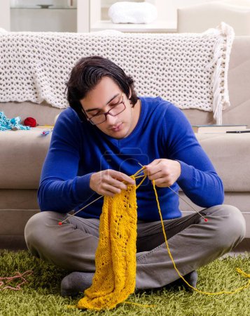 Foto de El joven hombre guapo tejiendo en casa - Imagen libre de derechos