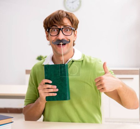 Téléchargez les photos : L'étudiant avec fausse moustache livre de lecture - en image libre de droit