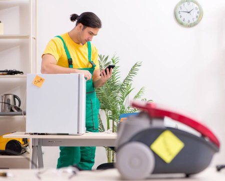 Téléchargez les photos : The man repairman repairing vacuum cleaner and fridge - en image libre de droit