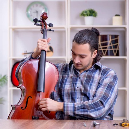 Téléchargez les photos : Le jeune réparateur beau réparateur de violon - en image libre de droit