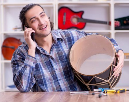 Photo for The young handsome repairman repairing drum - Royalty Free Image