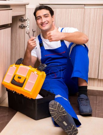 Foto de El joven reparador trabajando en la cocina - Imagen libre de derechos