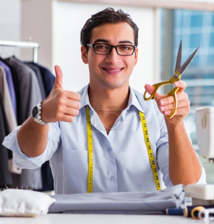 Téléchargez les photos : Le jeune homme tailleur travaillant sur de nouveaux vêtements - en image libre de droit