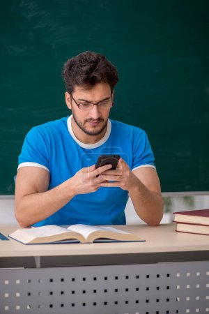 Photo for Young student holding smartphone in the classroom - Royalty Free Image