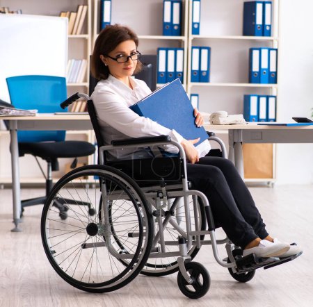 Foto de La empleada en silla de ruedas en la oficina - Imagen libre de derechos