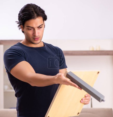Téléchargez les photos : Le jeune homme réparant des meubles à la maison - en image libre de droit