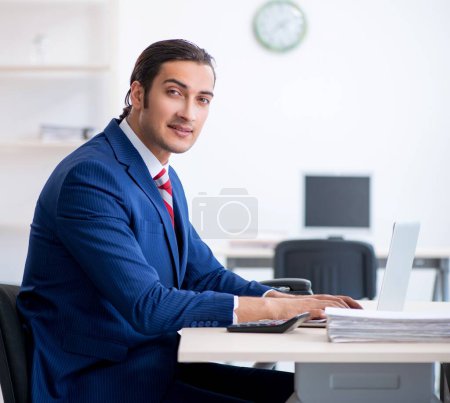 Téléchargez les photos : Le jeune homme d'affaires assis dans le bureau - en image libre de droit