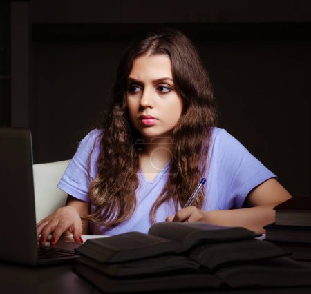 Foto de La joven estudiante preparándose para los exámenes tarde en casa - Imagen libre de derechos