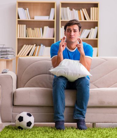 Foto de El hombre viendo fútbol en casa sentado en el sofá - Imagen libre de derechos